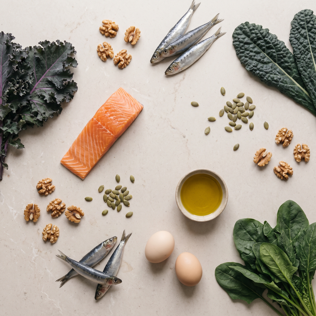 Flatlay met zalm, sardines, walnoten, pompoenpitten, eieren en bladgroenten