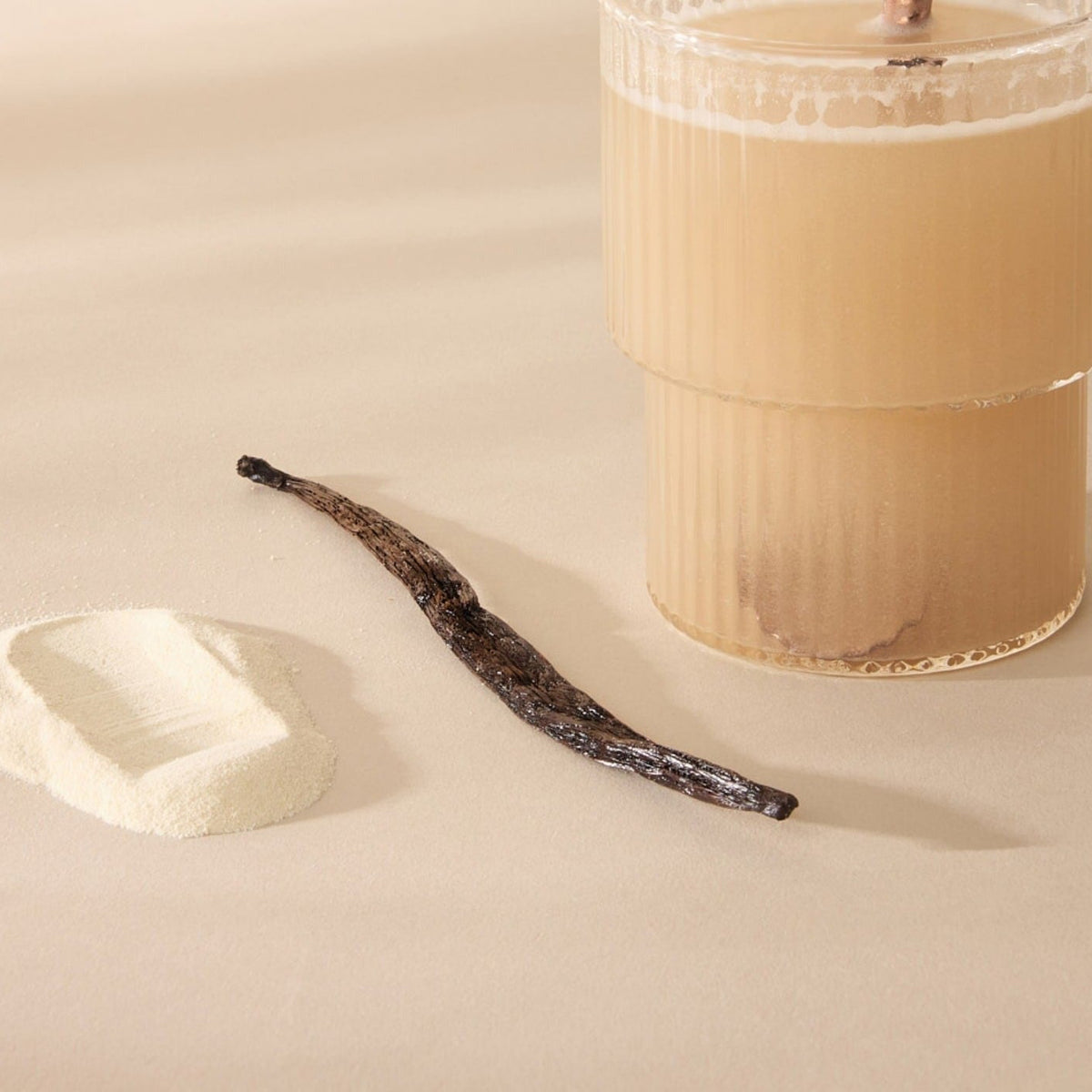 Glas met opgeloste Multi Collagen Protein+, poeder en een vanillestokje